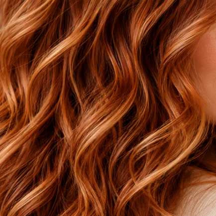 Nahaufnahme von glänzendem, kupferrotem Haar mit definierten Wellen, warmen Farbreflexen und lebendiger Haarstruktur.